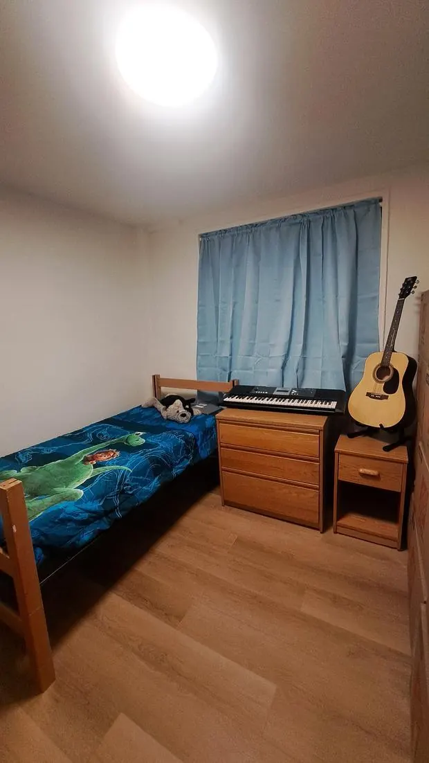 A child's bedroom with a twin bed, oak dresser, nightstand, keyboard, and guitar